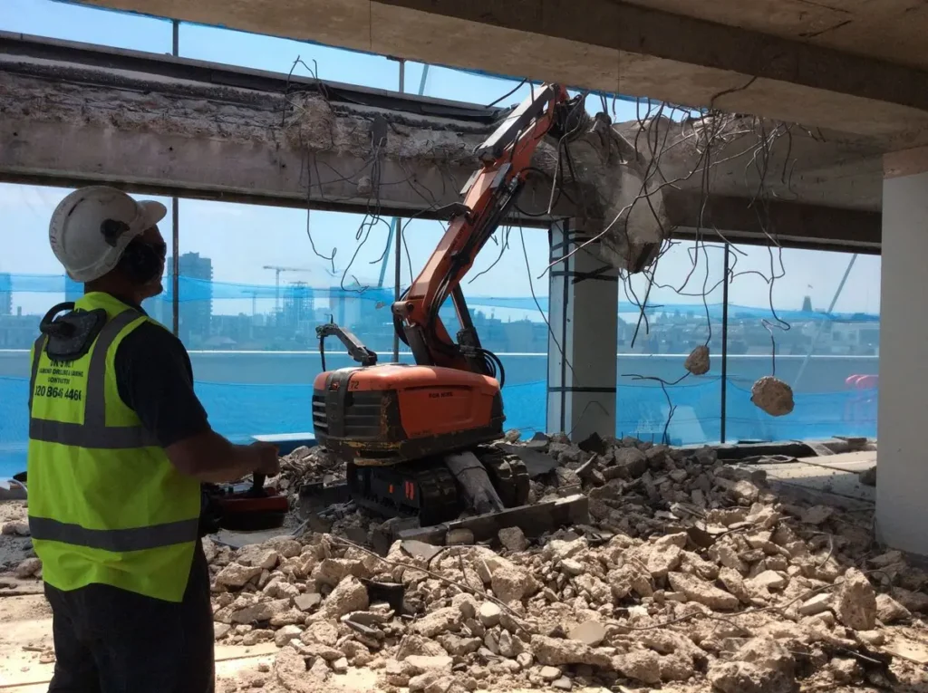 Mini-excavator cu ciocan hidraulic spărgând un perete, în zona Rahova